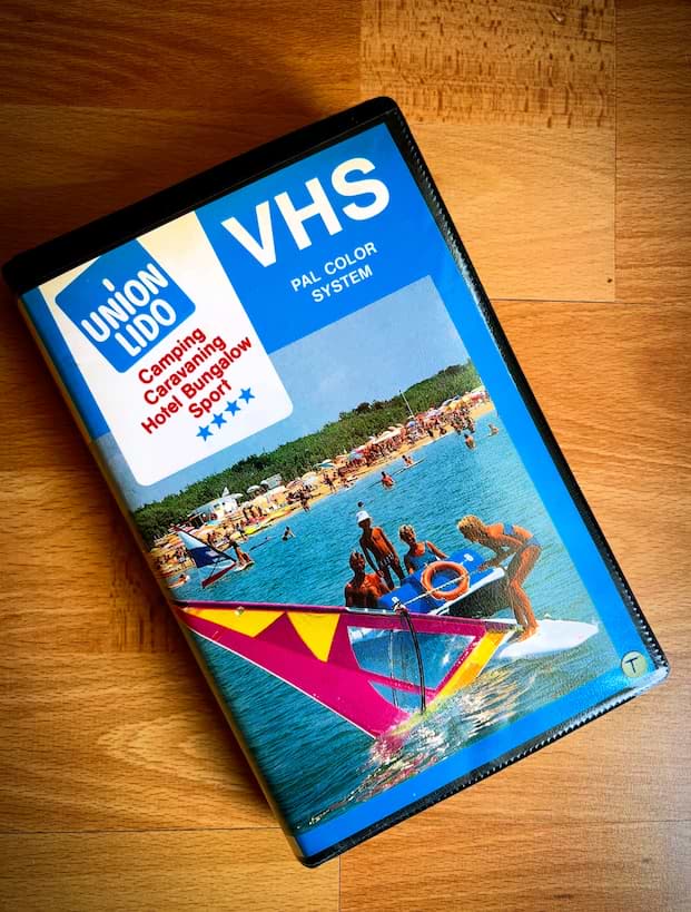 HS-Videokassette von Union Lido mit einem Titelbild, das Wassersport auf dem Meer und den Strand mit Sonnenschirmen zeigt. Das Cover trägt das Union-Lido-Logo sowie die Aufschrift „Camping, Caravanning, Hotel, Bungalow, Sport“ und „VHS PAL Color System“.