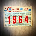 Historische Gästekarte des Camping NSU Lido in Cavallino (Venezia) aus dem Jahr 1964. Die mehrsprachige Karte in Italienisch, Deutsch, Englisch und Französisch berechtigt den Inhaber und seine Begleitpersonen zur bevorzugten Aufnahme im Campingplatz. Sie zeigt das historische Camping-NSU-Lido-Logo sowie Abbildungen eines Caravans und eines Zeltes.