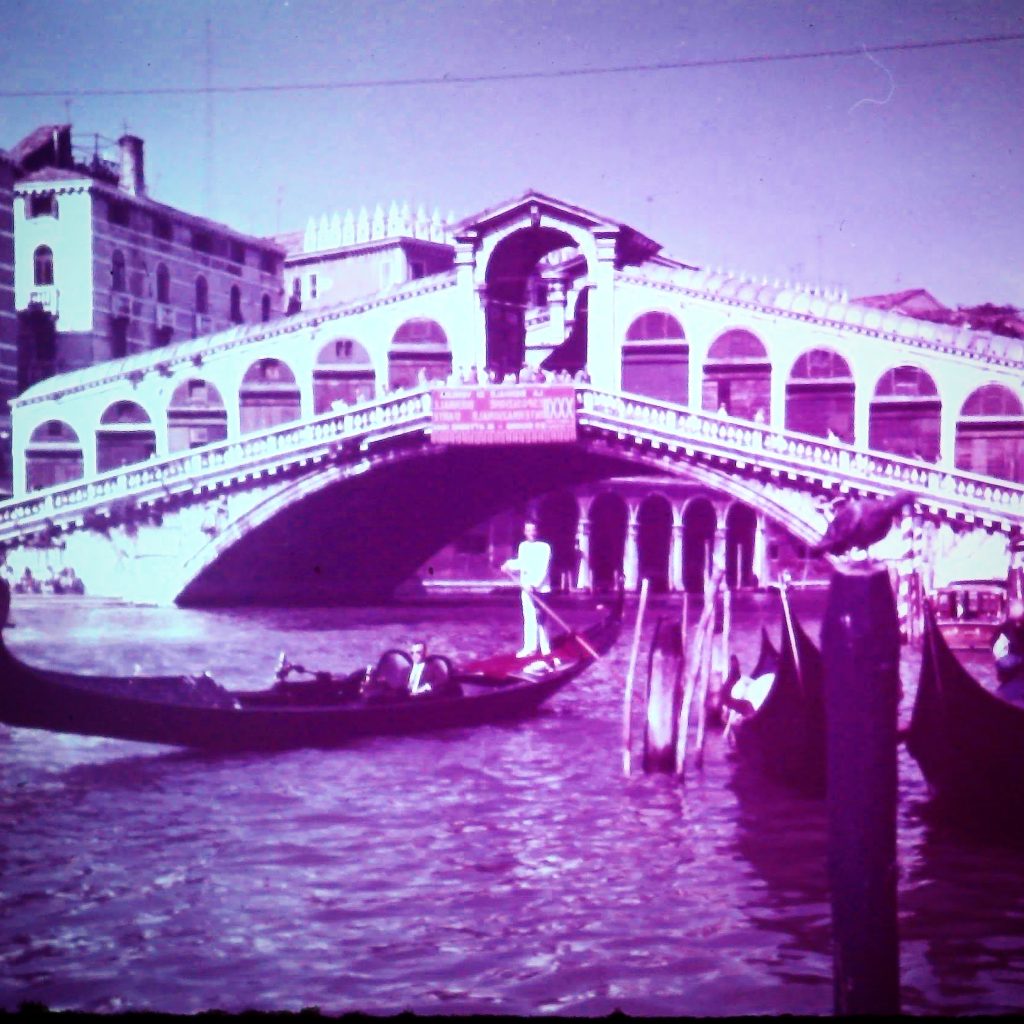 Historische Aufnahme der Rialtobrücke in Venedig mit Gondeln und Booten auf dem Canal Grande.
